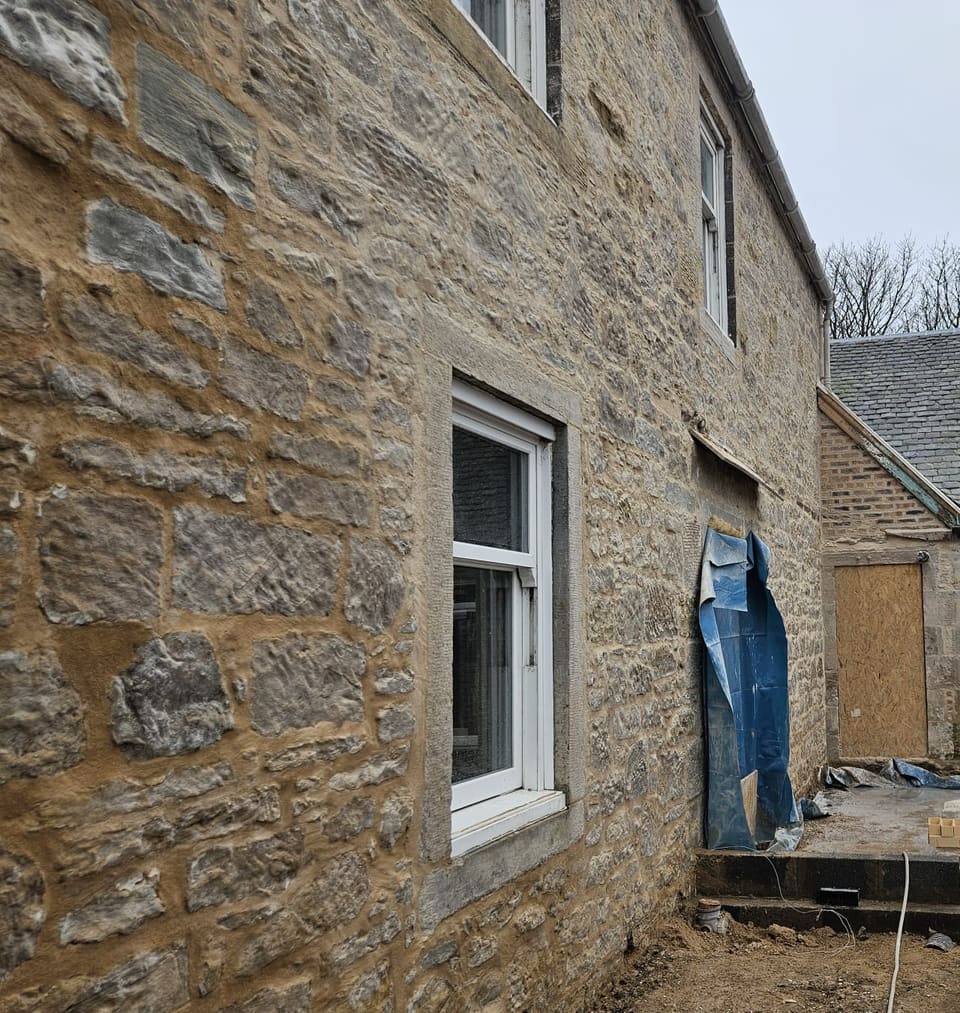 Repointed rubble wall with buff lime mortar filling the joints close to the stone faces.