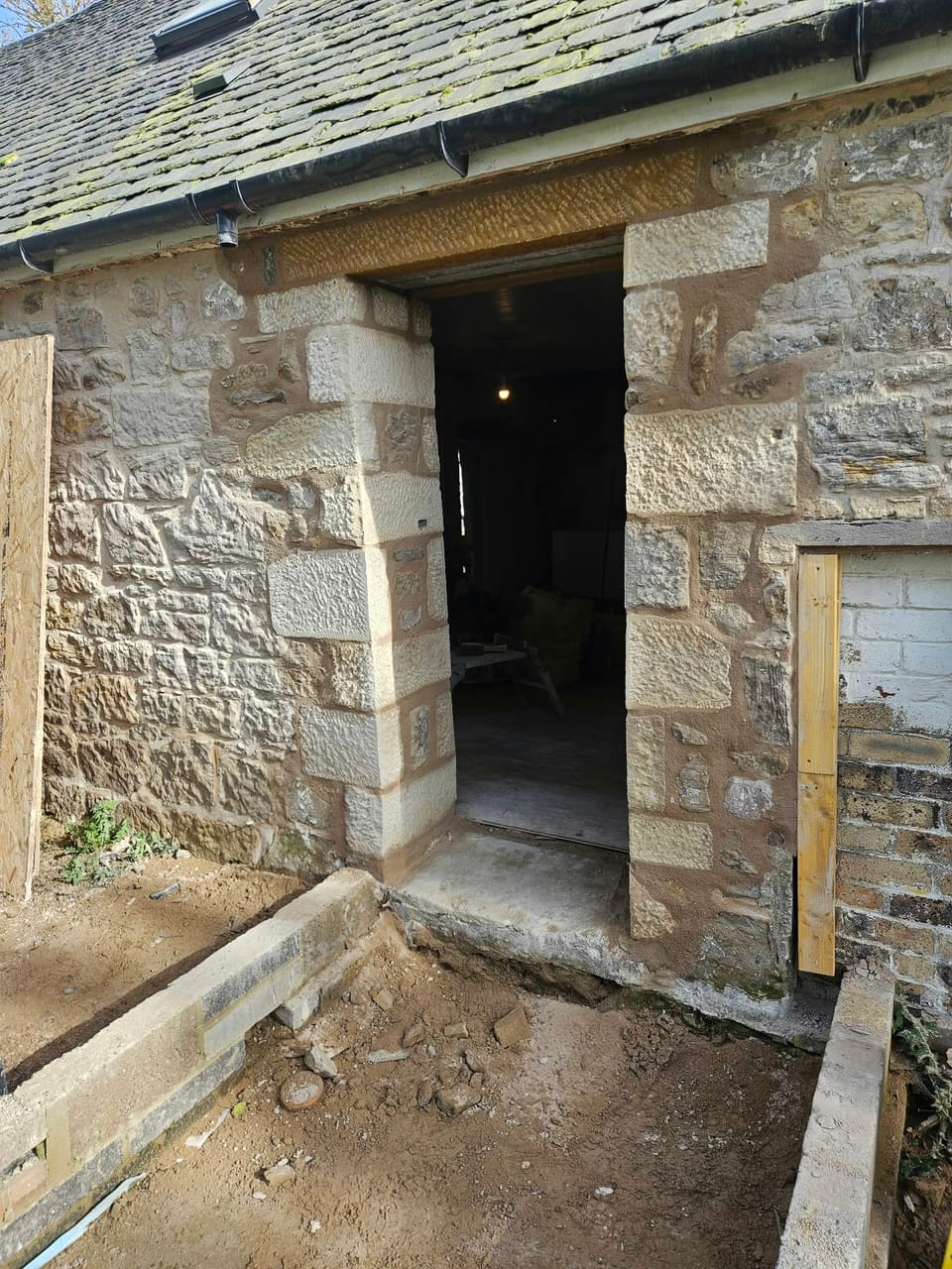 Doorway in a rubble stone wall with new sandstone rybats of alternating long and short stones and a new lintel.