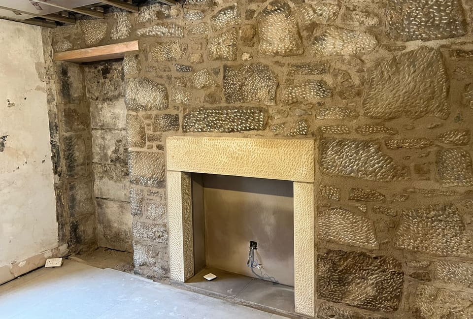 The finished stone wall and sandstone fireplace surround seen from the left.
