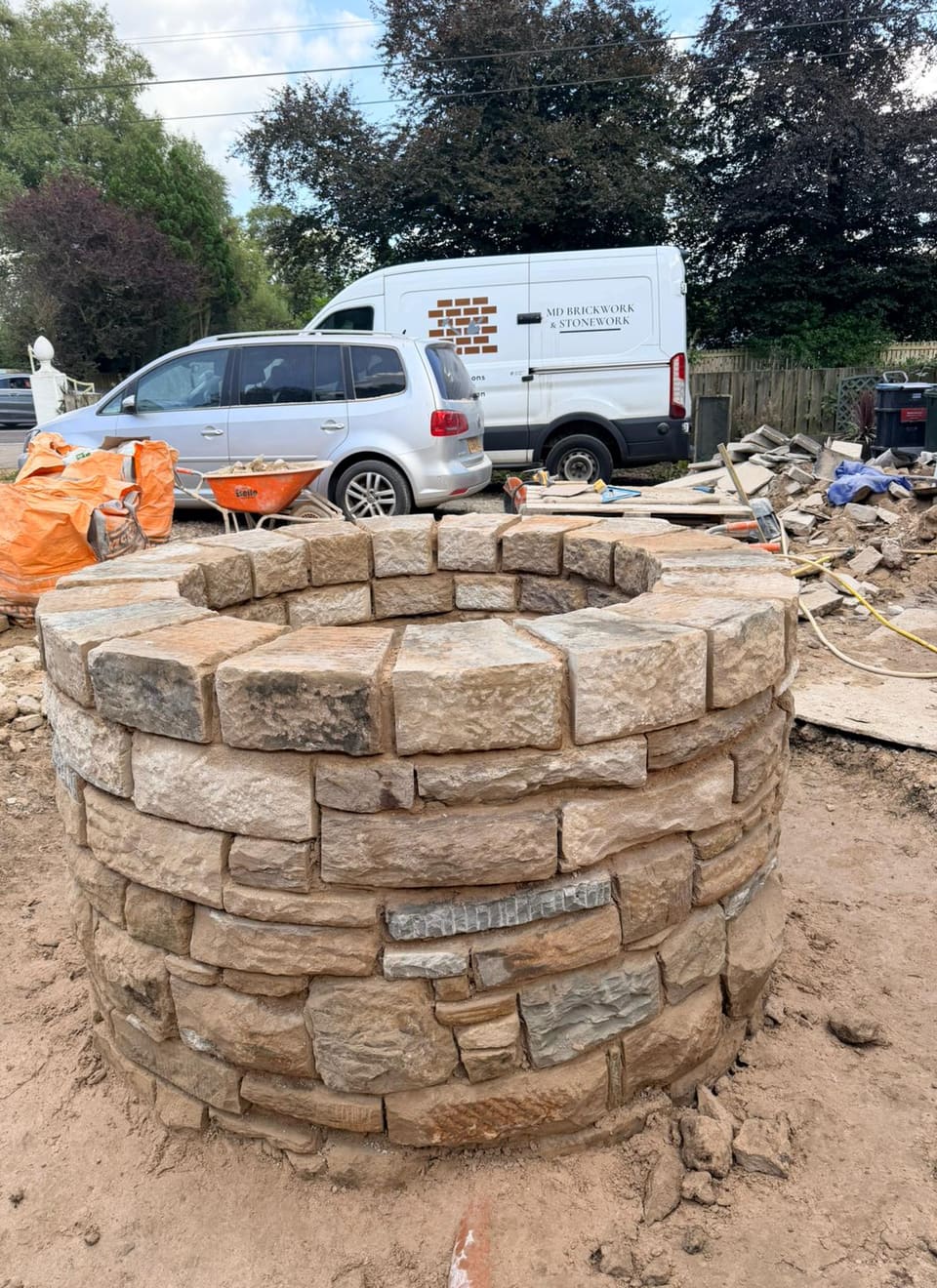 Round stone well head at full height with the coping stones laid on top and the joints not yet pointed.